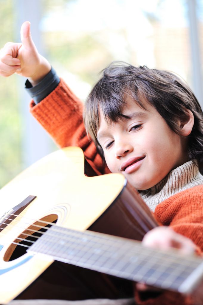 Kid playing guitar at home Smiling boy plays the guitar
